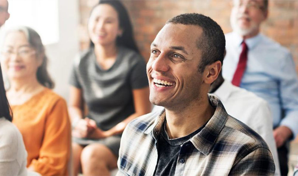 Smiling man in a small audience of people