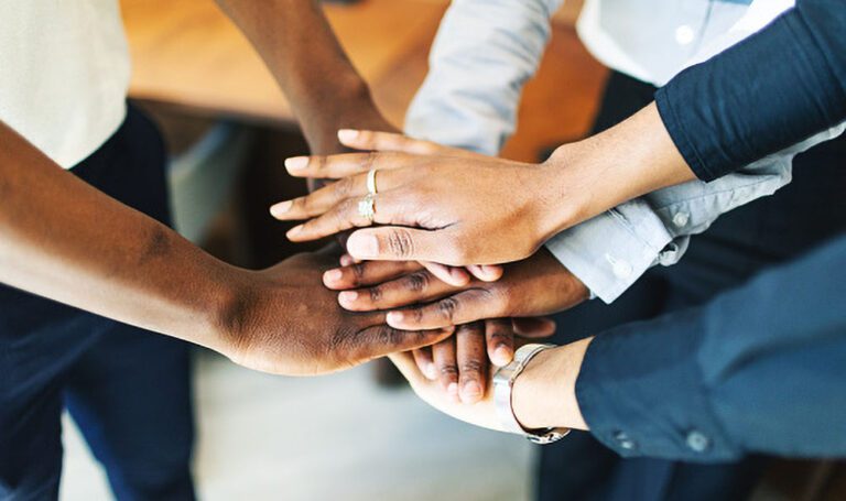 Business team putting hands together in the middle of a circle at the office.