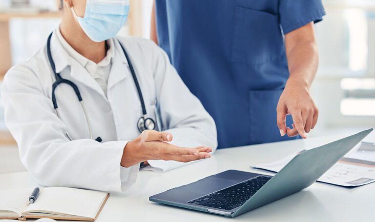A stock image with a doctor and nurse discussing something on their computer.
