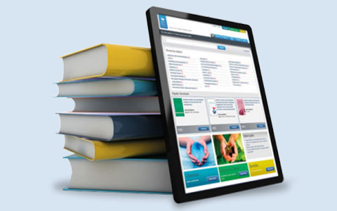 An iPad resting on a stack of colorful books.
