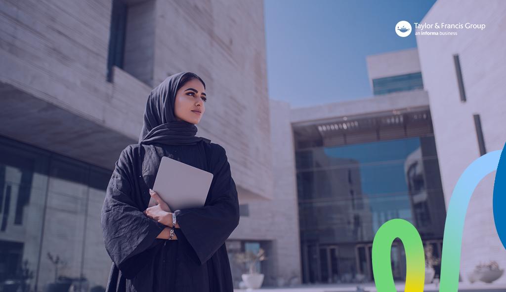 Student standing outside a university in the UAE, holding her laptop, and visualising her future